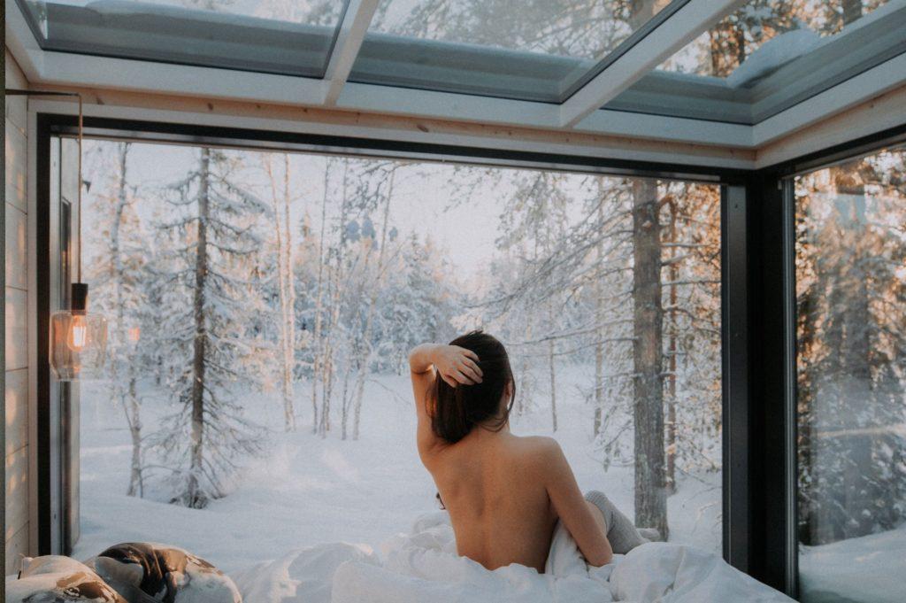 nainen herää kuurun lasikattoisesta sviitistä talvella