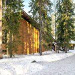 Lumisen metsän keskellä on hirsirakennus. /  In the middle of the snowy forest is a log building. Kuva: Sami Säily.