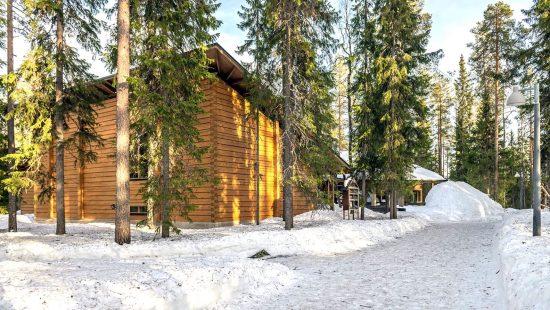 Lumisen metsän keskellä on hirsirakennus. /  In the middle of the snowy forest is a log building. Kuva: Sami Säily.
